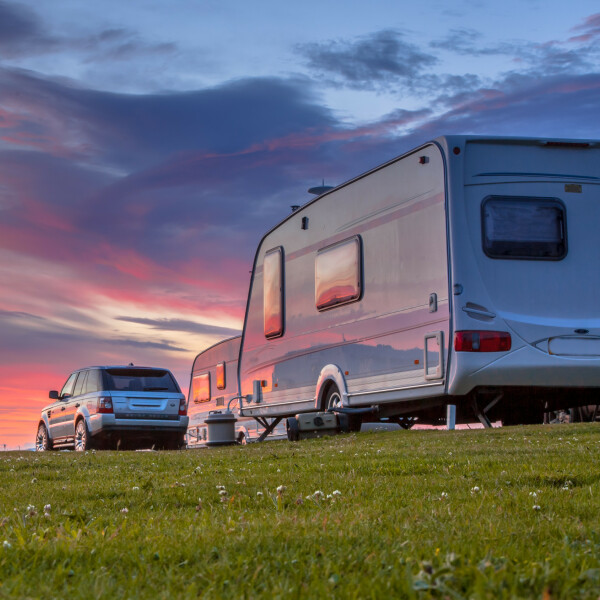 RV attached to a car driving at sunset